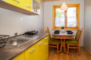 een keuken met gele kasten en een tafel met stoelen bij Domek AMPERO in Władysławowo