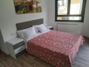 a bedroom with a bed with a red comforter at Edificio Valles del Lúpulo in Astorga
