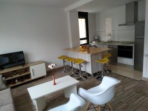 a kitchen with a white table and yellow chairs at Edificio Valles del Lúpulo in Astorga