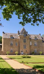 un grand bâtiment en briques avec un arbre devant lui dans l'établissement Château de Cadouzan, à Saint-Dolay