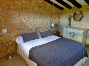 a bedroom with a bed and a stone wall at La Era De Pepe in Calaceite