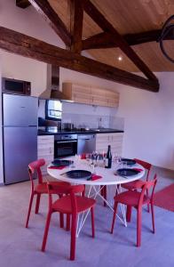 een keuken met een witte tafel en rode stoelen bij Gîtes Du Mas de Surlan in Chantemerle-les-Blés