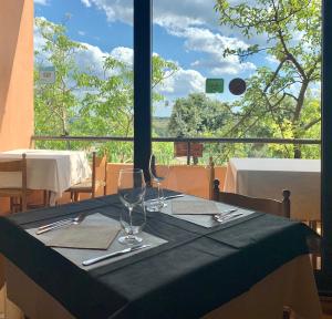 una mesa con dos copas de vino y una ventana en Hotel Miramonti Seulo Turismo Rurale, en Seùlo