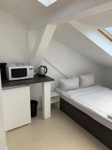 ワルシャワにあるApartamenty Hoża Attic Studioのベッド1台、電子レンジ付きのカウンターが備わる客室です。