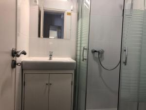 een witte badkamer met een wastafel en een douche bij 99 Flowers Flat in Lissabon