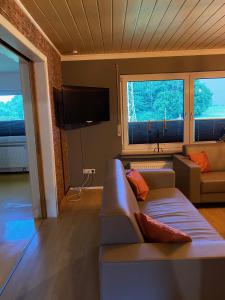 a living room with a couch and two windows at Ferienhaus Tannenhof in Birgel