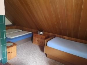 2 Betten in einem kleinen Zimmer mit Holzwänden in der Unterkunft Haus Franziska in Leck