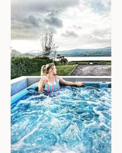 una ragazza seduta in una vasca idromassaggio di Skellig Port Accomodation - Sea View Rooms Ensuite a Portmagee