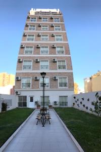 wysoki budynek z dwoma stołami piknikowymi przed nim w obiekcie Apart Hotel Granada w mieście Neuquén