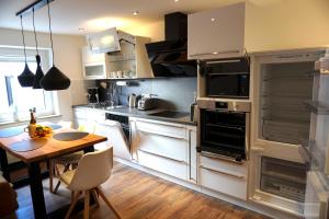 a kitchen with white cabinets and a wooden table with a dining room at Tier- & kinderfreundliches Ferienhaus - KEINE MONTEURE in Priesendorf