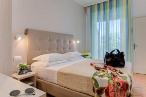 Un dormitorio con una cama grande con un bolso negro. en Hotel Cimarosa, en Riccione