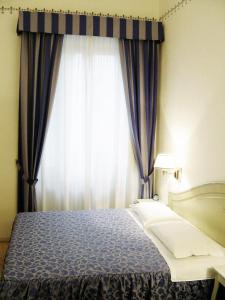 a bedroom with a bed and a window with curtains at Casa Gori in Certaldo