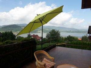 a yellow umbrella on a balcony with a view of the water at Dom nad Jeziorem in Mucharz