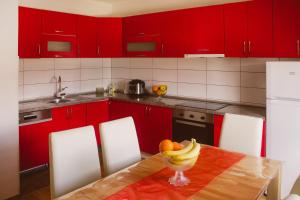 eine Küche mit roten Schränken und einem Tisch mit einer Schale Obst in der Unterkunft Golden House in Sarajevo
