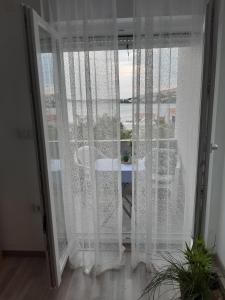 Habitación con ventana y cortinas blancas. en Varaždinci, en Rogoznica