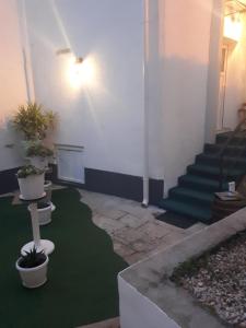 a room with stairs and a green floor with potted plants at Apartments Petra 23 in Mali Lošinj