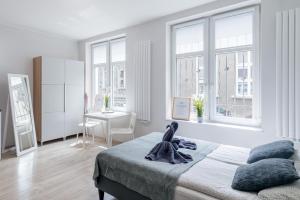 a white bedroom with a bed and windows at Apartment New & Nice in Gdańsk
