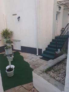 ein Gebäude mit einem grünen Boden mit Treppen und Topfpflanzen in der Unterkunft Apartments Petra 23 in Mali Lošinj
