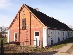 an old brick building with a fence in front of it at Lehnenhof in Dargun