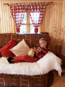 Un joven acostado en un sofá leyendo un libro en Holiday cottage & food Plav, en Plav