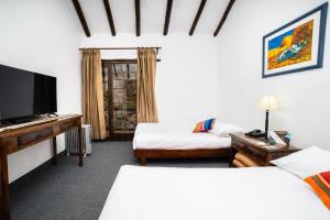 a hotel room with two beds and a flat screen tv at Amak Valle Sagrado in Urubamba