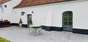 a patio with a table and chairs next to a white building at Demeure de charme haut de gamme - Piscine chauffée in Lissewege