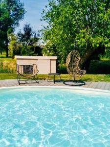 twee stoelen en een tafel naast een zwembad bij Demeure de charme haut de gamme - Piscine chauffée in Lissewege