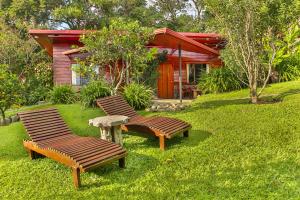 a row of wooden benches in a grassy area at Arco Iris Lodge in Monteverde Costa Rica