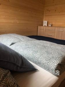 a bed in a room with a wooden wall at Stajnia Bocianie Gniazdo in Uniejow