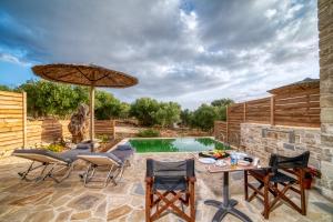 een patio met een tafel en stoelen en een parasol bij Olive Luxury Suites - ADULTS ONLY in Kamilari