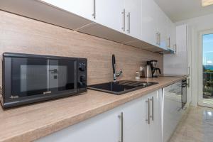 a kitchen with a microwave and a counter with a sink at Apartment Vivien in Crikvenica
