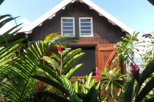 - un bâtiment en bois avec une porte dans un jardin dans l'établissement Bungalow Chez Madly, à Saint-François 2 autres photos