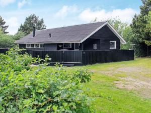 a black house with a fence in front of a yard at 4 person holiday home in R m in Lakolk