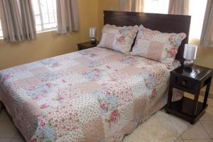 1 dormitorio con 1 cama con edredón y almohadas en Chrinas Guest House, en Lilongwe