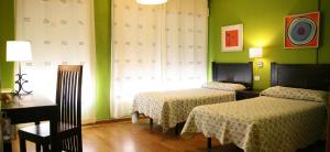 a room with two beds and a table and a window at Casa Matías in Sarria