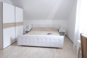 a white bedroom with a white bed and a mirror at Villa Melody in Bohinj