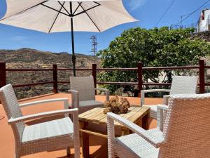 einen Tisch und Stühle mit einem Sonnenschirm auf einer Terrasse in der Unterkunft Juncalillo House in Gáldar
