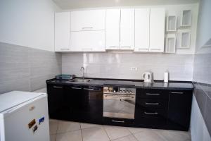 una cucina con armadi bianchi e piano cottura di Apartman Black Star a Novi Sad