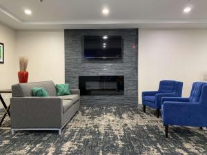 een woonkamer met een bank en 2 blauwe stoelen bij Best Western Plus Olive Branch Hotel & Suites in Olive Branch
