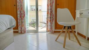einen weißen Stuhl in einem Zimmer mit einem Schlafzimmer in der Unterkunft Casa da Cerca Ferragudo Beach Caves Hiking Golf in Ferragudo