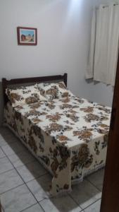 een bed in een slaapkamer met een bruine en witte deken bij Apto Aconchegante Enseada Azul com Wi-Fi in Guarapari
