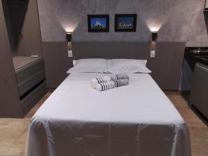 a bedroom with a large white bed with two pillows at KIT/LOFT - MUITO PRÓXIMA AO AEROPORTO DE BRASÍLIA in Brasília