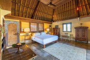 a bedroom with a bed and a table in a room at Villa Angsa by Nakula in Sanur +25 photos