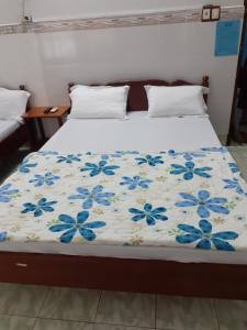 a bed with a blanket with blue flowers on it at Thanh Binh Hotel in Buon Ma Thuot