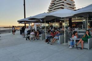 un groupe de personnes assis à des tables sous des parasols sur la plage dans l'établissement studio cabines 6 couchages 150 m de la plage et à quelques secondes des commerces wifi gratuit, à La Grande Motte