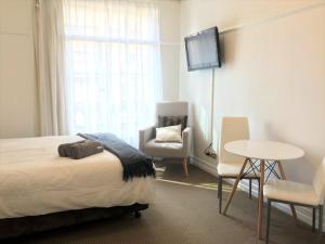 a bedroom with a bed and a table and a tv at Brisbane City Apartments (Central Station) in Brisbane