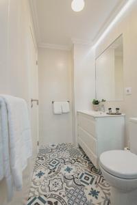 a white bathroom with a toilet and a sink at Vibrant Host - Heroismo's Metro in Porto +47 photos