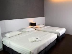 
a hotel room with two beds and a lamp at Hotel Zamburger Chariton Ipoh in Ipoh
