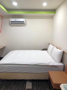 a bedroom with a bed with a air conditioner on the wall at Well Live Hotel in Douliu