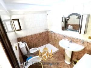 ein Badezimmer mit einem Waschbecken und einem WC mit einer Krone darauf in der Unterkunft Paradise Palm Beach Apartment in Sarande in Sarandë
